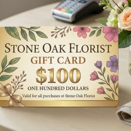 Florist gift card with illustrated flowers on a table beside a small vase of roses and hydrangeas.