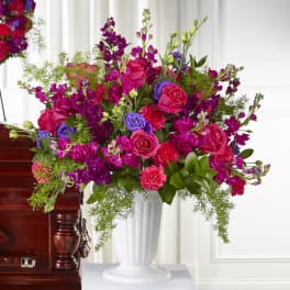 Bright pink and purple floral arrangement in a white vase