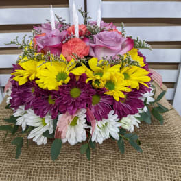 Colorful floral centerpiece with roses, daisies, and candles