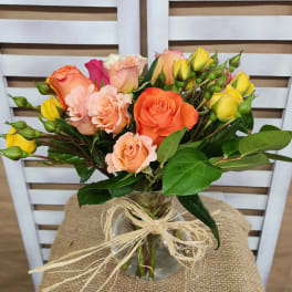 Bouquet of orange, peach, and yellow roses in a glass vase