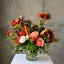 Mixed bouquet of roses, lilies, and chrysanthemums in a glass vase