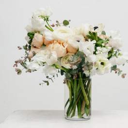 White and blush flowers arranged in a clear glass vase