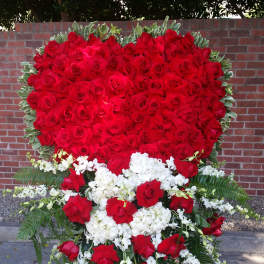 Heart-shaped red rose standing spray with white flowers on an easel