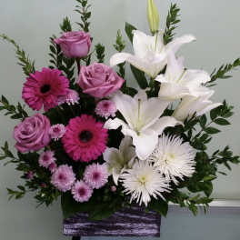 Pink roses and white lilies arranged in a purple container