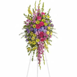 Tall standing floral spray with pink, purple, and yellow flowers on an easel