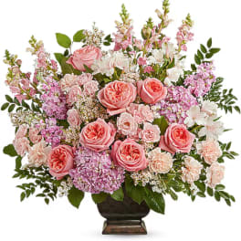 Pink and white floral arrangement in a dark pedestal vase