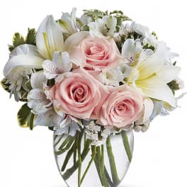 Pink roses and white lilies in a clear glass vase