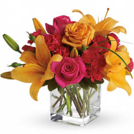 Pink roses and yellow lilies arranged in a clear glass vase