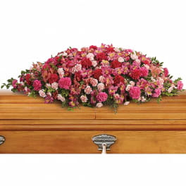 Pink and red floral casket spray on a wooden casket