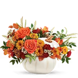 Orange and yellow floral arrangement in a white pumpkin vase