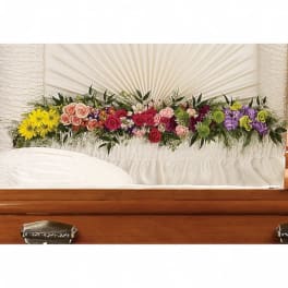 Colorful floral spray arranged across a white casket