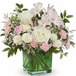 Pink and white flowers arranged in a green glass vase