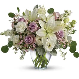 Lavender roses and white lilies in a clear glass vase