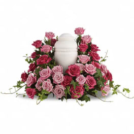 Pink and red roses arranged around a white urn
