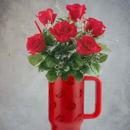 Red roses arranged in a red handled tumbler vase