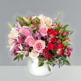 Mixed pink and red flower arrangement in a white vase