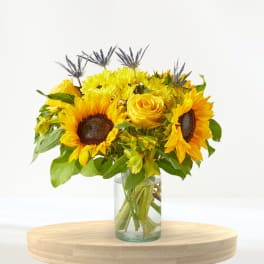 Sunflower and yellow rose bouquet in a clear glass vase