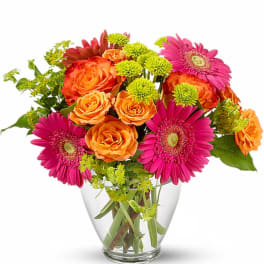 Bouquet of orange roses and pink gerbera daisies in a clear glass vase