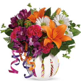 Colorful bouquet of lilies, daisies, and carnations in a white vase with ribbon curls