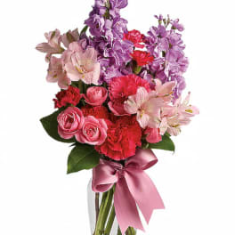 Pink and purple mixed bouquet in a clear vase with a satin ribbon