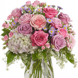 Bouquet of pink and lavender roses with small purple daisies in a glass vase