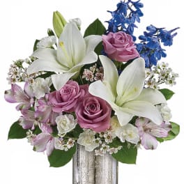 Bouquet of white lilies, pink roses, and blue flowers in a silver vase