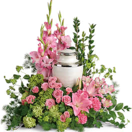 Pink lilies and roses arranged around a white urn