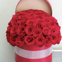 Large red rose arrangement in a round pink hat box
