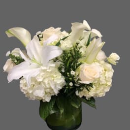 White lilies and roses arranged in a glass vase