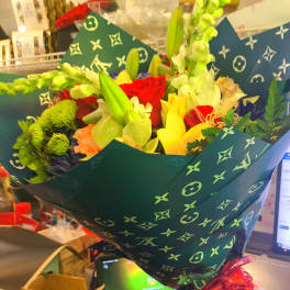 Bouquet of mixed flowers wrapped in dark patterned paper with a red ribbon