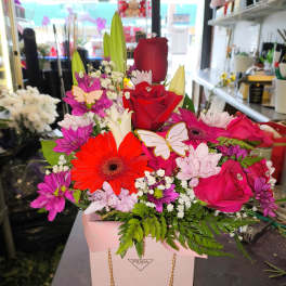 Bright mixed bouquet in a pink gift bag with roses and daisies