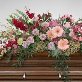 Floral spray of pink and red flowers on a wooden casket