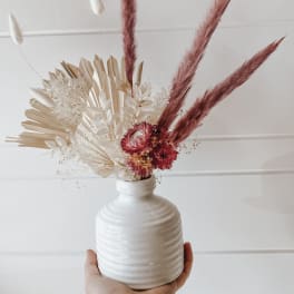 Dried floral arrangement in a white vase with pink and cream pampas grass