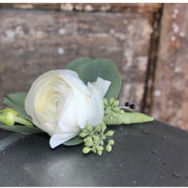 Small white ranunculus floral accent with berries and buds on a wet metal surface