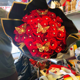 Bouquet of red roses with gold butterfly decorations in black wrap