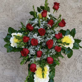 Cross-shaped floral tribute with red roses, white flowers, and yellow chrysanthemums