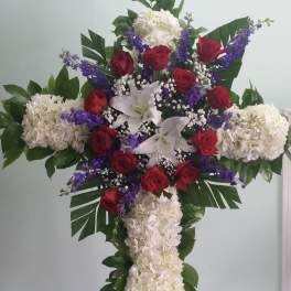 Cross-shaped floral arrangement with red roses, white lilies, and white hydrangeas