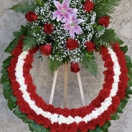 Standing floral wreath with red roses, pink lilies, and red-and-white garlands