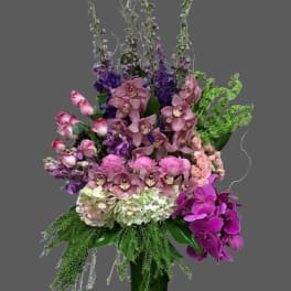 Tall bouquet of pink and purple flowers in a green vase