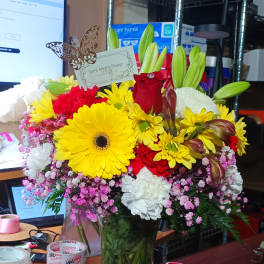 Mixed bouquet in a clear glass vase with yellow, red, and white flowers