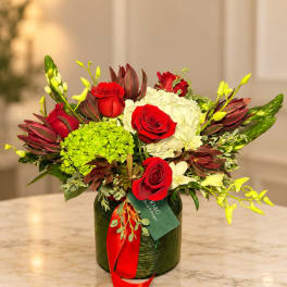 Red roses and white hydrangeas in a green vase with red ribbon