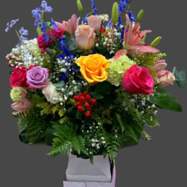 Mixed bouquet with roses, lilies, and blue delphinium in a box