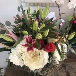 Large bouquet of lilies, roses, hydrangeas, and orchids in a glass vase