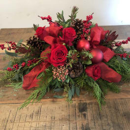 Red roses with pinecones, berries, and ribbon in a low holiday arrangement