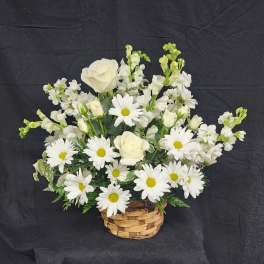 White roses and daisies arranged in a woven basket