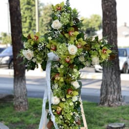 Large floral cross arrangement with white roses and green orchids