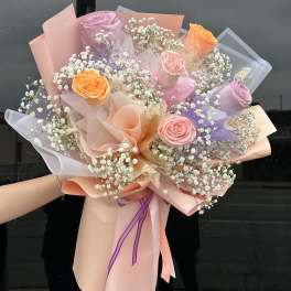 Bouquet of pastel roses and baby's breath wrapped in pink paper