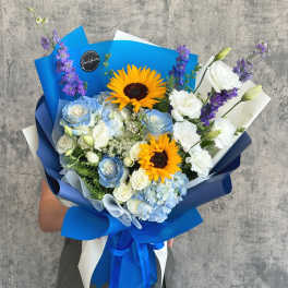 Bouquet of blue and white flowers with sunflowers wrapped in blue paper