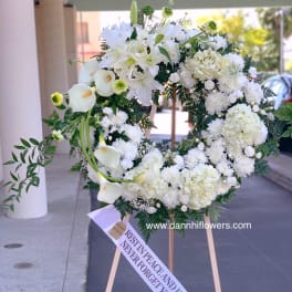 White funeral wreath on a wooden easel with a memorial ribbon