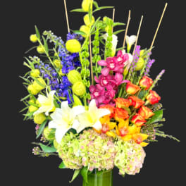 Tall mixed bouquet in a green vase with white lilies and bright orchids